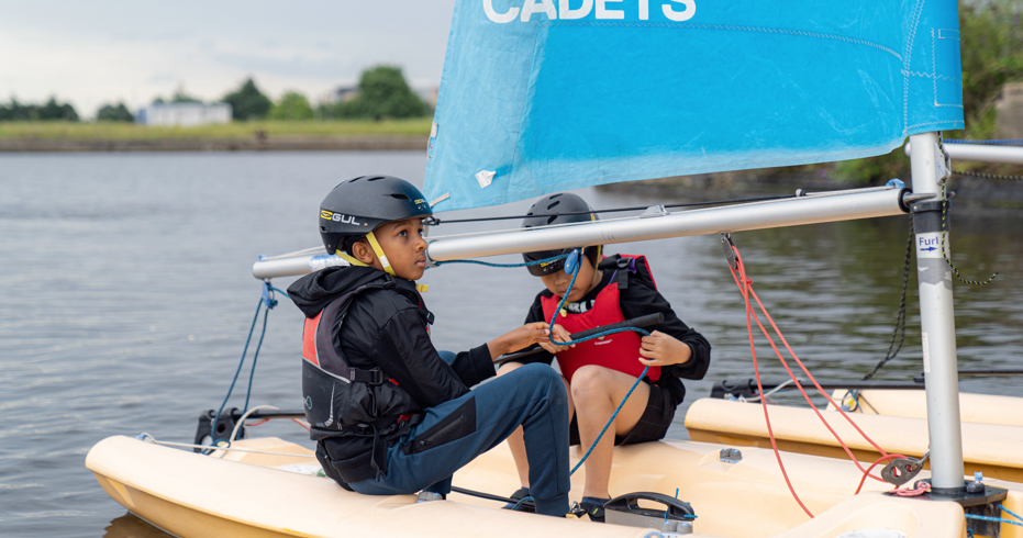 two young children sat in a dinghy on the water as part of sea cadets