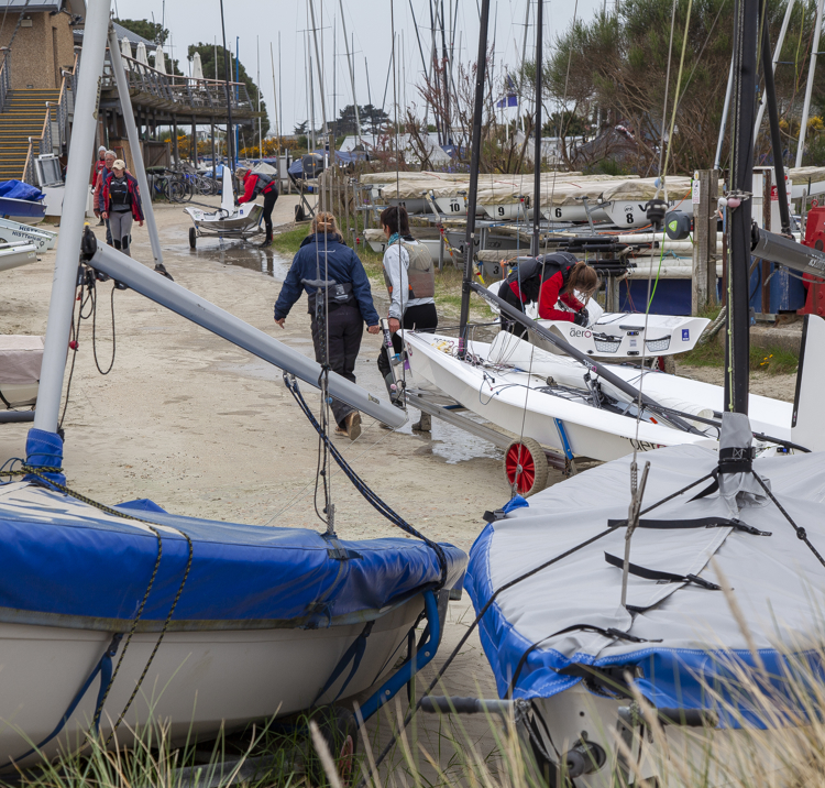 Sailing club volunteers walking their boat up to shore