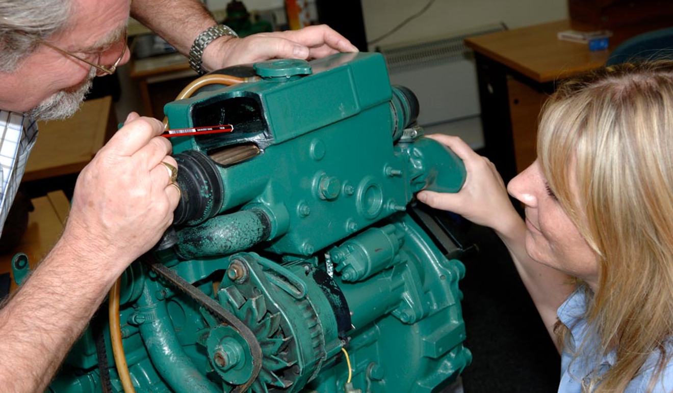 A teacher explaining engine maintenance to student
