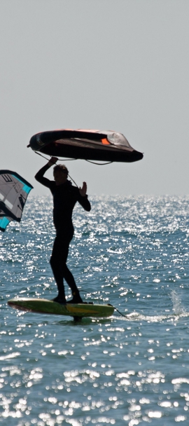 a silhouette of two wing surfers travelling through sparkling water