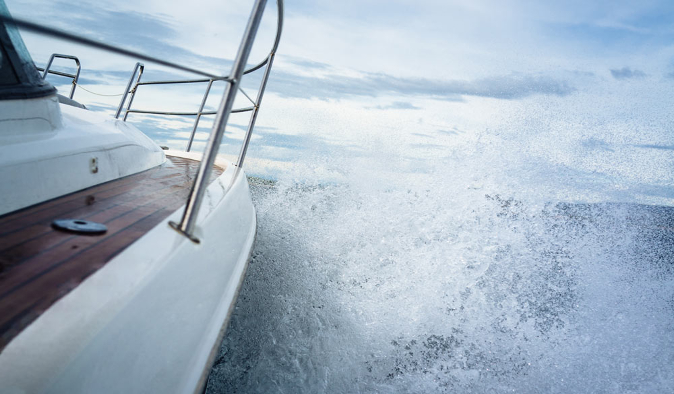 close up of side of motor cruiser hitting wave and creating a large spray