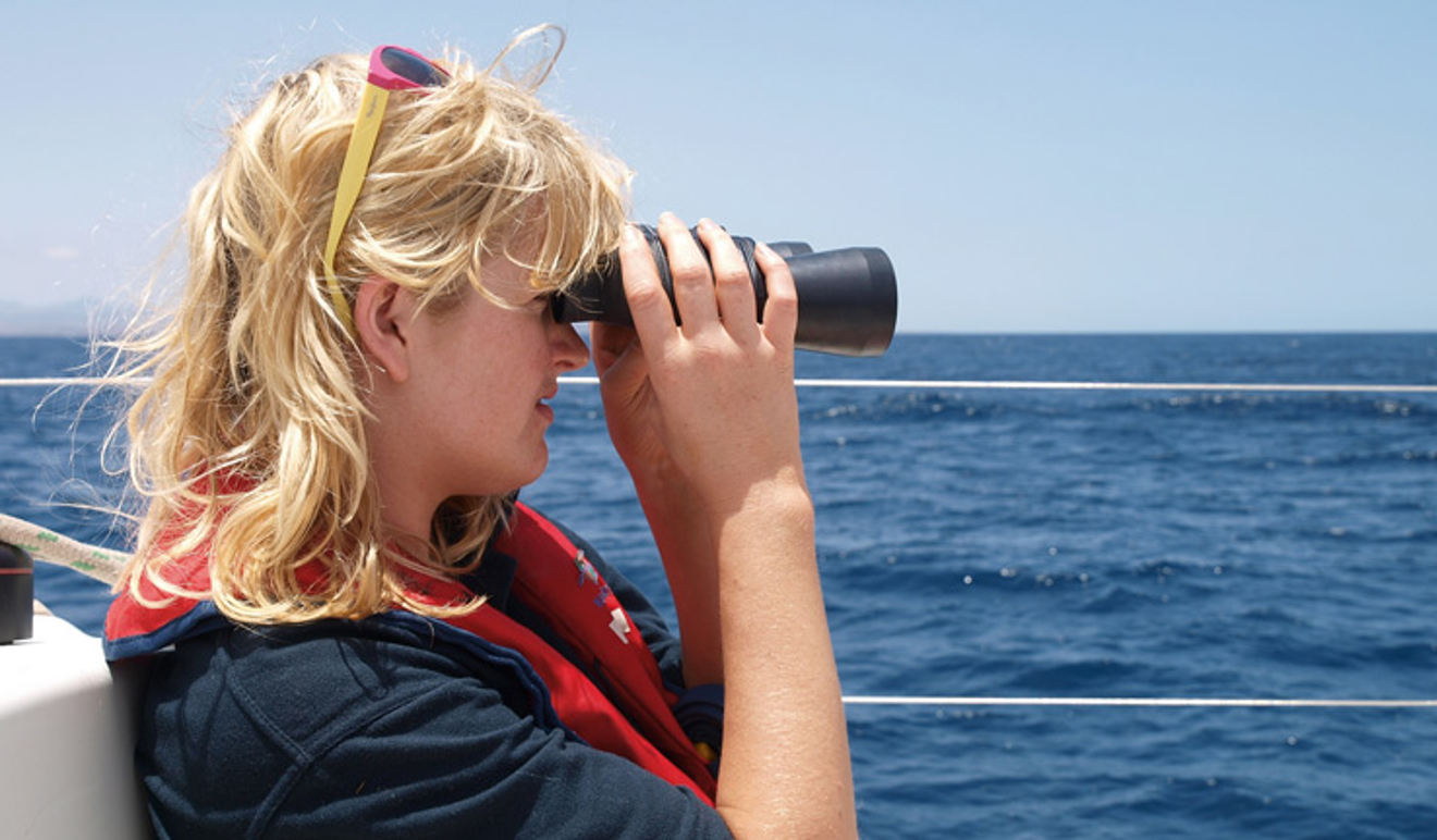 woman on boat using binoculars
