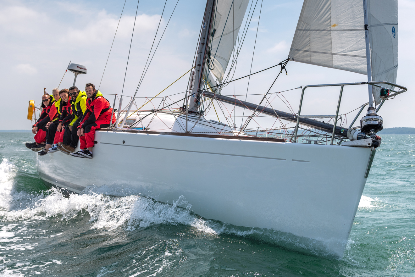 Sail cruising crew hanging off the side of their boat