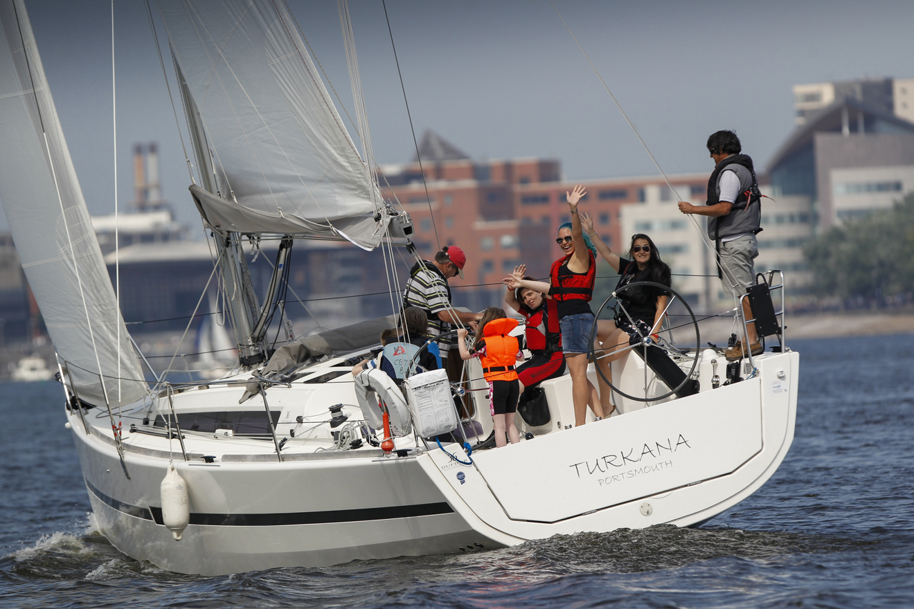 Group of women on a yacht smiling and waving at the camera