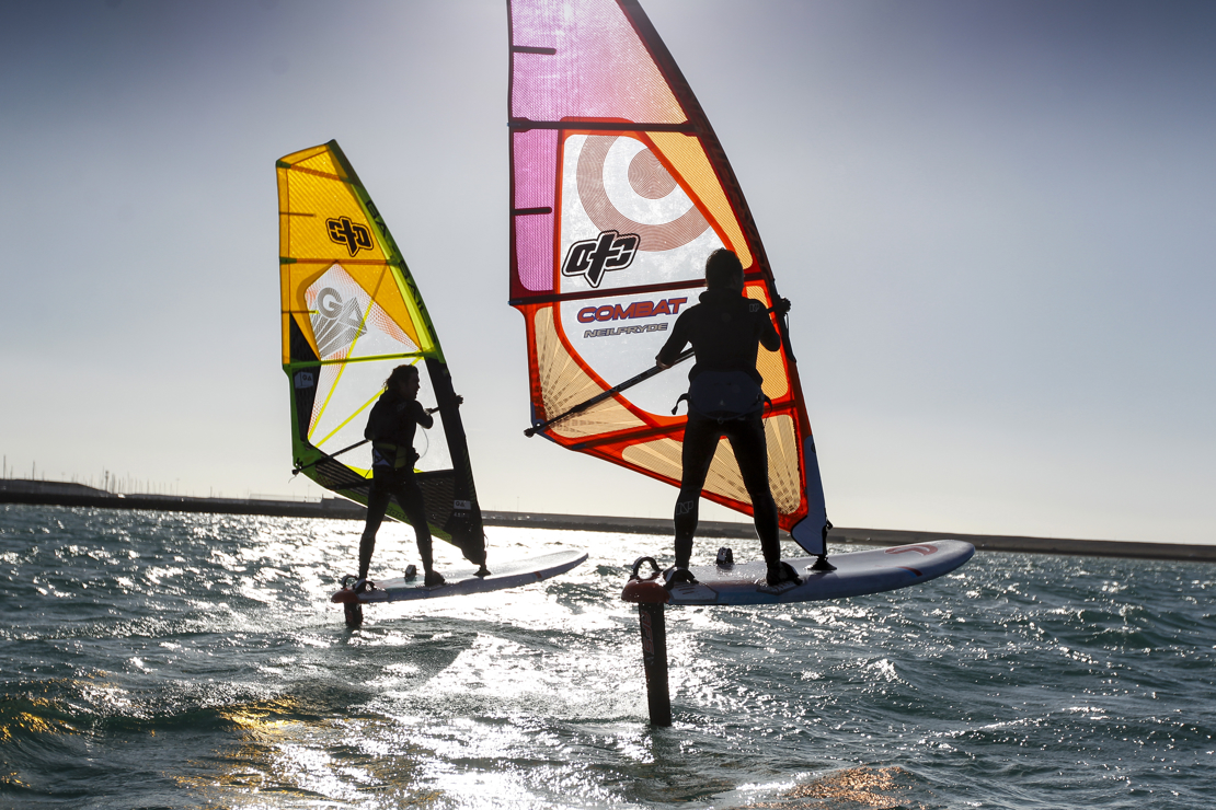 silhouettes of windsurfers at sunset