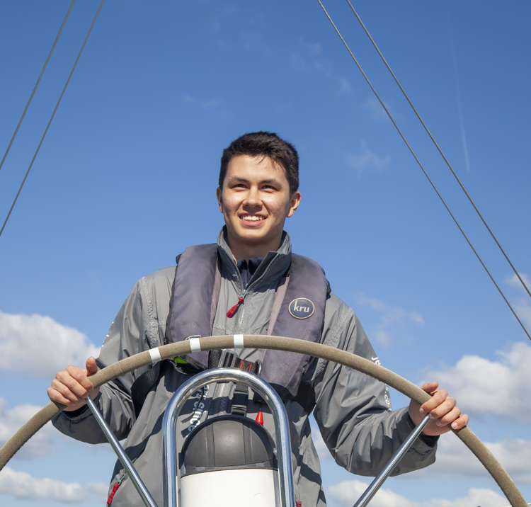 man standing at the helm smiling