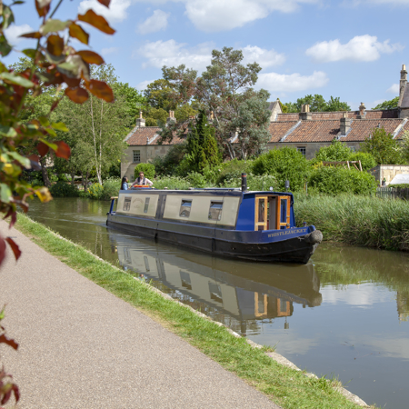 Canal boat cruising along the inland waterways on a beautiful day