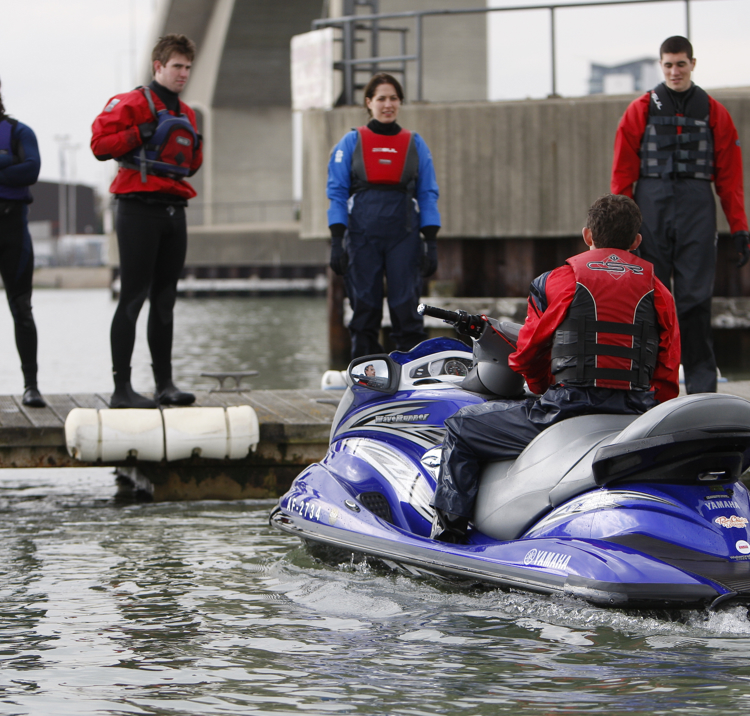man sat on jet ski with course mates watching