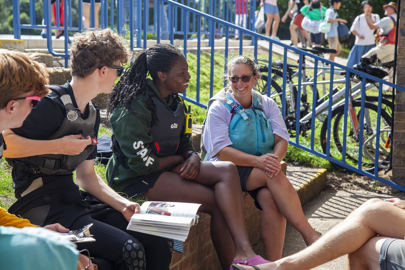 young women sitting on wall talking to a group of people