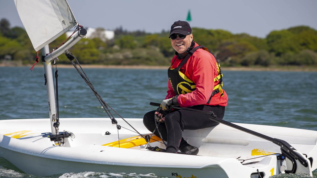 sailor in a dinghy smiling at the camera