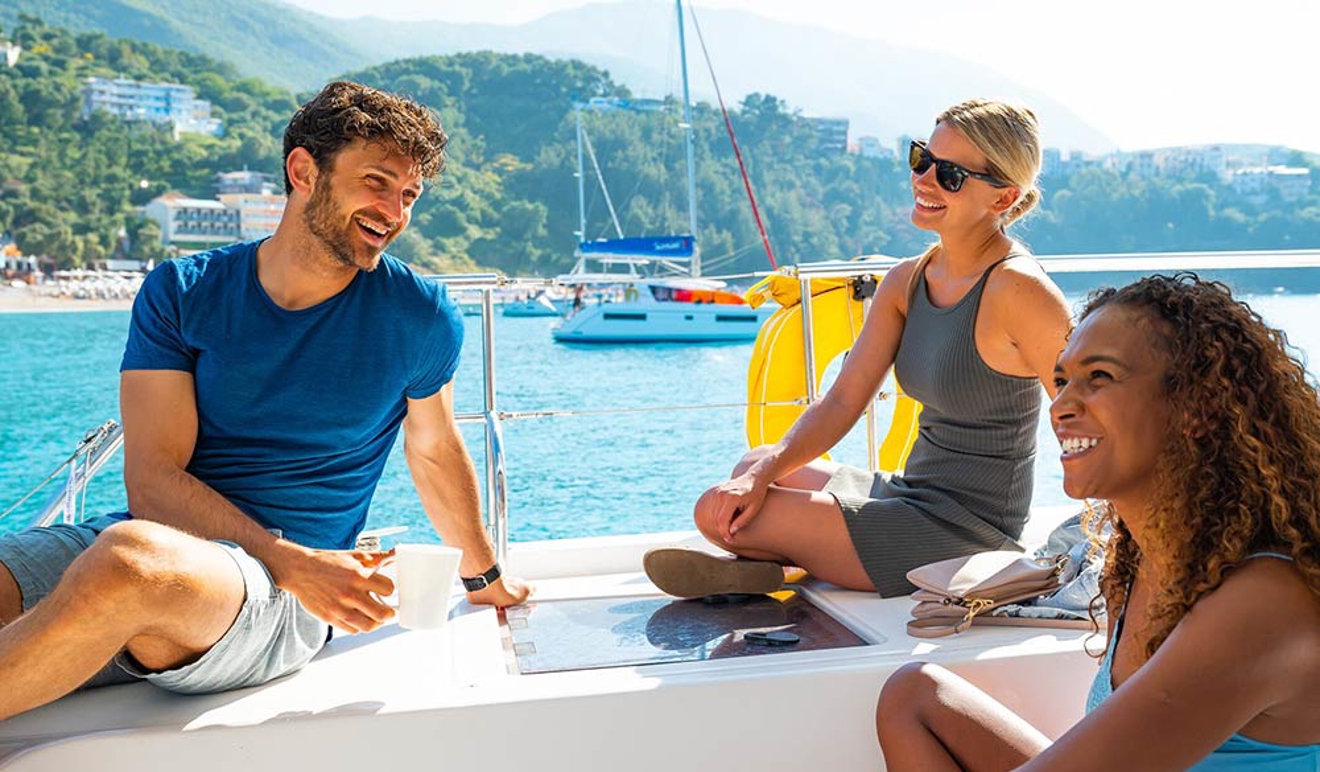 Three people on a boat on holiday smiling and laughing