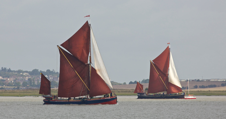 Classic sailboats cruising a river