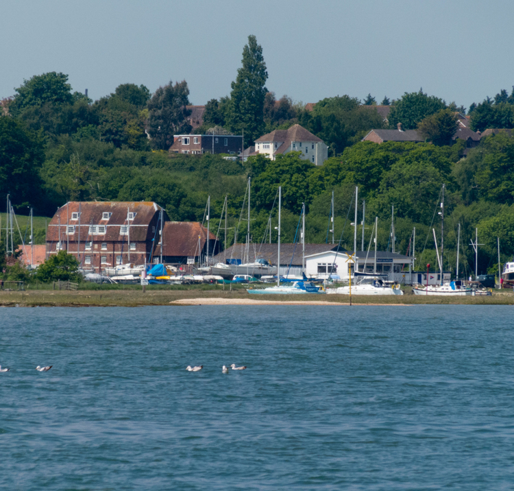 View of a river in the foreground and sailing club in the background