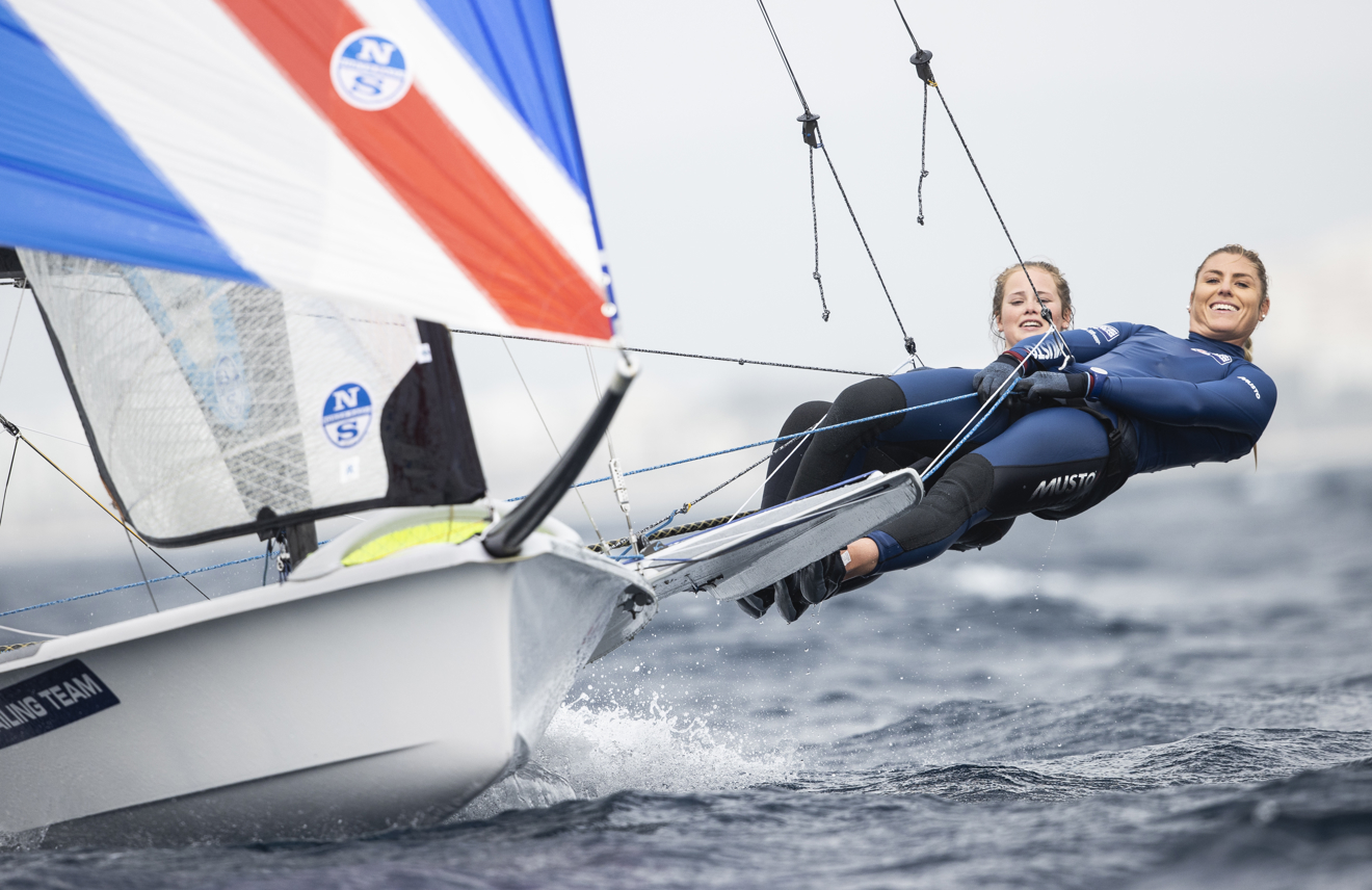 Crew4Gold team female athletes by the boat sailing by the water with smiling faces