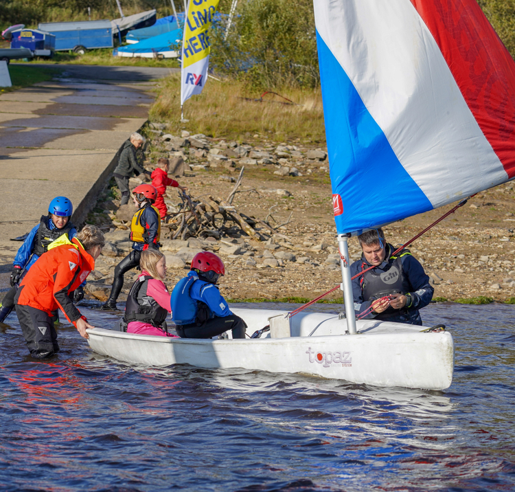 Children in the water getting ready for a dinghy sailing session
