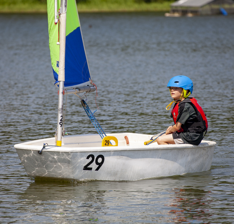 Wide shot of child sailing their single hander dinghy 