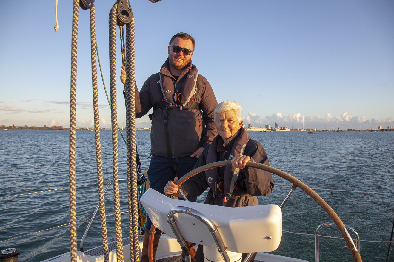 Man and woman sailing a boat at dusk
