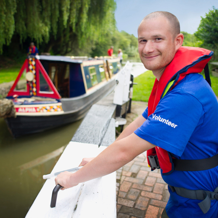 Volunteer helping a narrowboat by operating a lock  