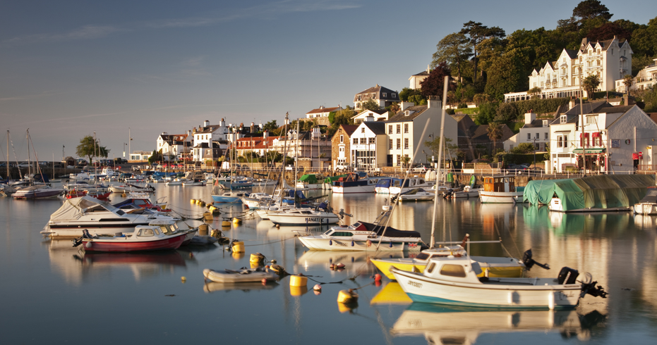 beautiful harbour with various different boats moored up in line in the water