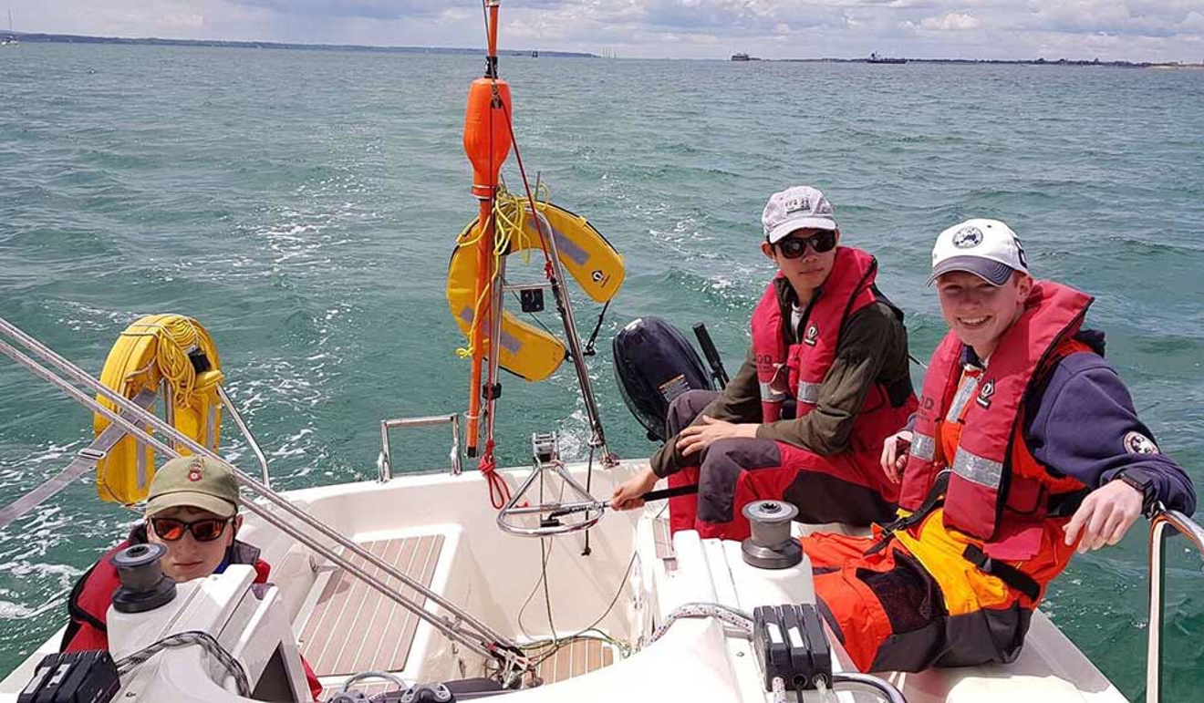 three young men sat on a yacht