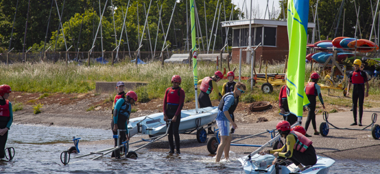 A group of boys are pulling dinghies out of the water.