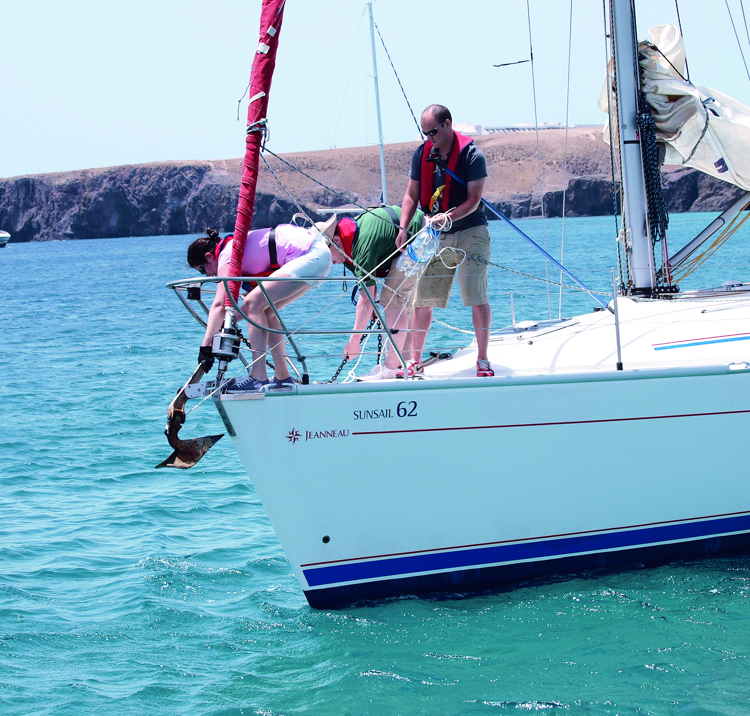 Wide shot of crew on a yacht anchoring with care