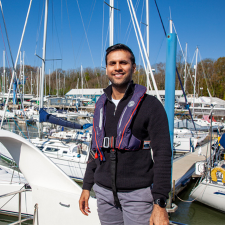 sailor posing and smiling in front of boat