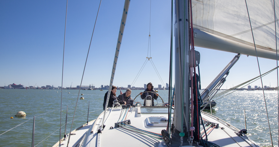 3 people sailing a boat on the open water
